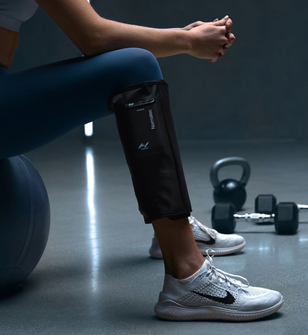 Person som sitter på gymmet med Normatec Lower Legs